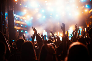 A concert venue with a crowd of people raising their hands.