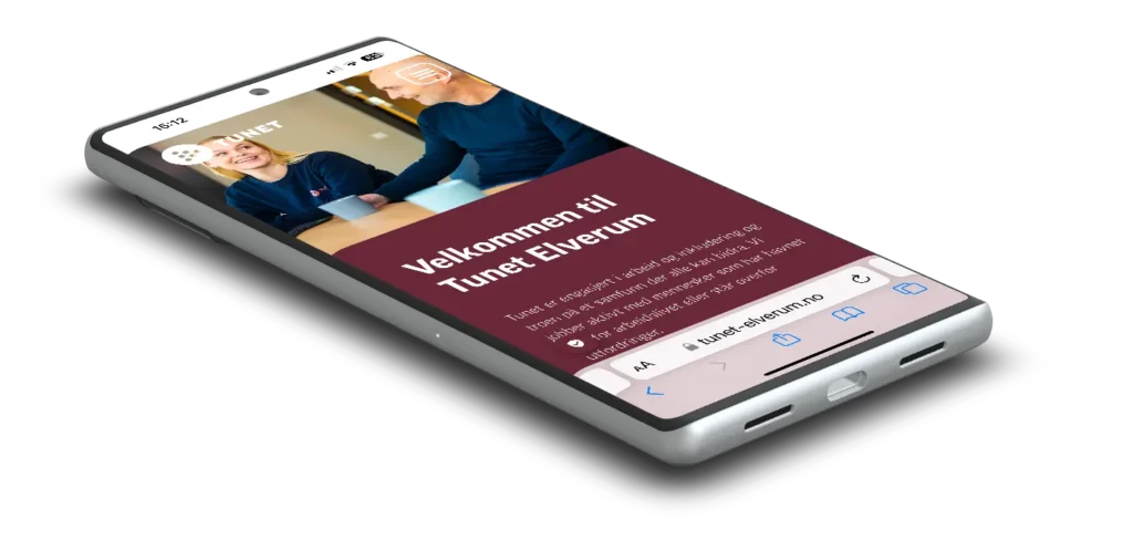 En smarttelefon viser et nettsted på norsk med tittelen "Velkommen til Tunet Elverum" med et bilde av to personer som håndhilser i bakgrunnen på skjermen, og fremhever Arbeidsinkluderingsbedriften Tunet Elverums engasjement for fellesskap og inkludering.