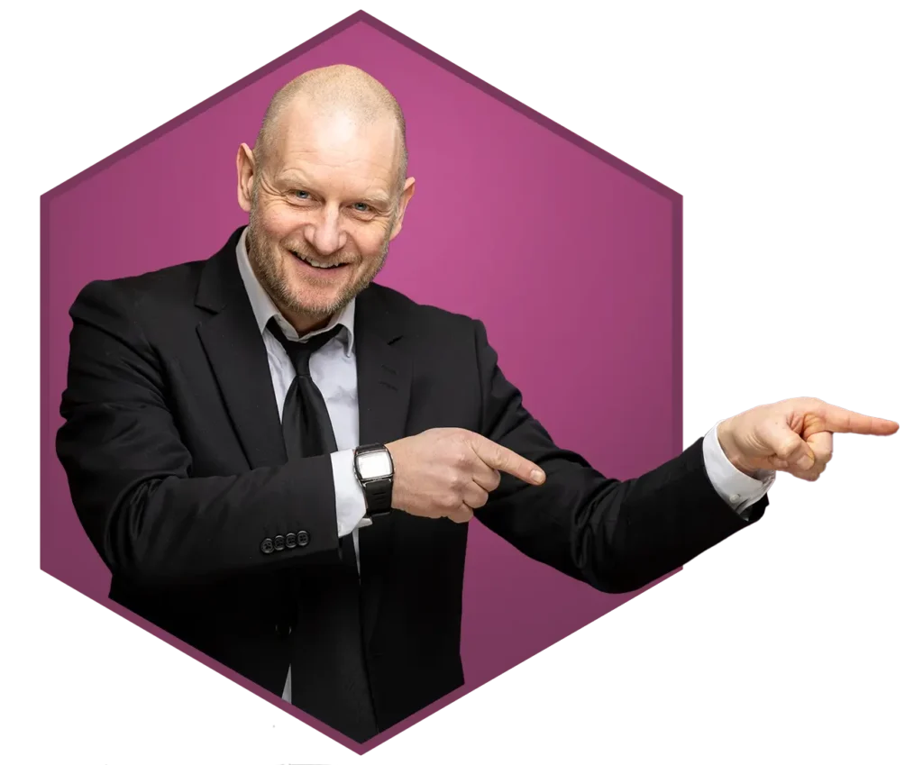 En skallet mann i svart dress og slips smiler og peker til høyre, står foran en lilla sekskantet bakgrunn, noe som antyder suksess innen digital markedsføring.