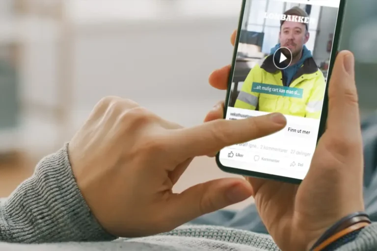 En person bruker en smarttelefon til å se på en rekrutteringsfilm med en mann i gul vernejakke.